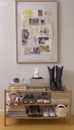 there is a shelf with shoes and books on it in front of a framed picture