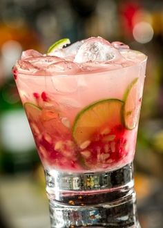 a close up of a drink in a glass with ice and garnishes