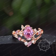 a ring with pink stones and leaves on it, sitting on top of a black box