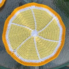 a crocheted lemon sitting on top of a metal pan covered in yellow and white yarn