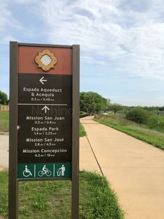 a sign that is on the side of a road in front of grass and dirt