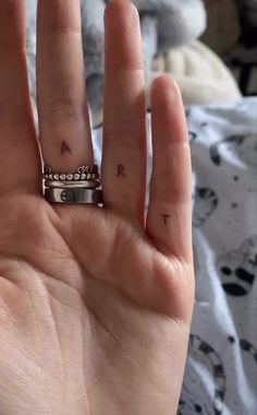 a person's hand with a ring on it and two small tattoos on their fingers