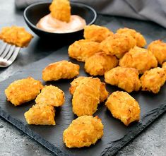 some fried food is on a black plate with a fork and spoon next to it