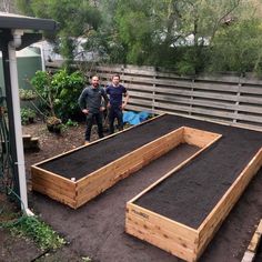 two men standing next to a raised garden bed