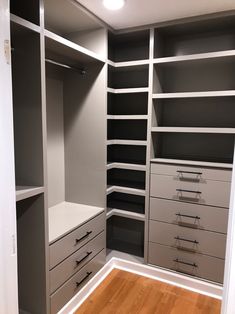 an empty walk in closet with gray and white shelves, drawers and lights on the ceiling