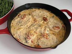 a skillet with green beans and chicken in it next to a red bowl filled with green beans