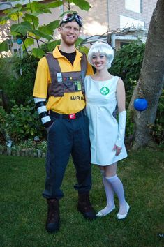 a man and woman dressed up in costumes standing next to each other on the grass