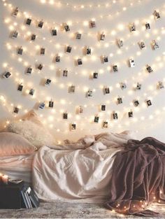 a bedroom with lights strung from the ceiling and pictures on the wall above the bed