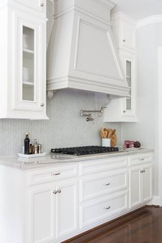 a kitchen with white cabinets and wood floors