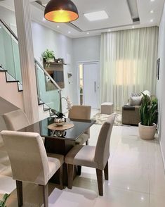 the dining room table is surrounded by beige chairs and white tile flooring, along with a staircase leading up to the second floor