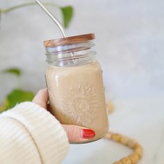 a person holding a mason jar with a straw in it