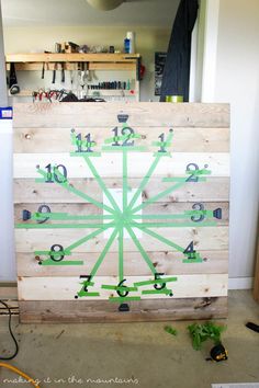 a clock made out of wood with green tape on it's face and numbers painted on the sides