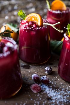 three glasses filled with red liquid and garnished with orange slices