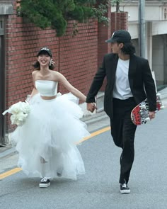 a man and woman are walking down the street holding hands while dressed in wedding attire