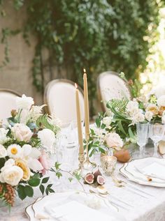 the table is set with white and pink flowers, gold place settings, and candles