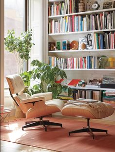 an eames chair and ottoman in front of a bookshelf