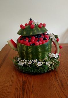 a watermelon teapot filled with fruit and flowers