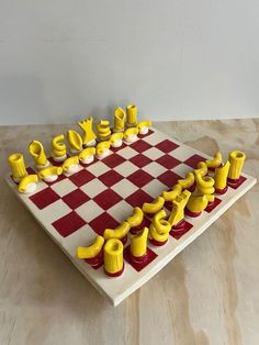 a chess board made out of yellow and red pieces on top of a wooden table