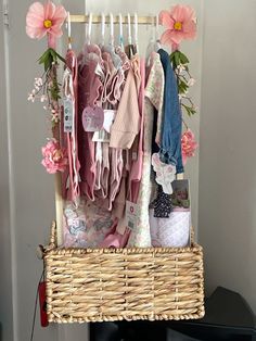 a wicker basket with clothes hanging from it's sides and flowers on the wall