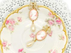 "These beautiful vintage inspired earrings were created with the sweetest pearl bow post earrings adorned with brass scalloped settings with pink and white Cameo cabochons and vintage cream teardrop pearls. These cameo statement earrings hang beautifully from the ear and measure 2 3/4 inches in length and 7/8 inches in width. These earrings make the \"perfect gift\" for your mom, sister, daughter, friend, girlfriend, wife or bridesmaids....She will truly love these and treasure them for many yea Cameo Drop Earrings For Wedding, Pink Pearl Charm Drop Earrings, Pink Feminine Pearl Earrings, Elegant Cameo Dangle Earrings, Vintage Pearl Charm Drop Earrings, Vintage Drop Earrings With Pearl Charm, Pink Pearl Bridal Earrings As Gift, Pink Pearl Bridal Earrings For Gift, Elegant Pink Dangle Clip-on Earrings