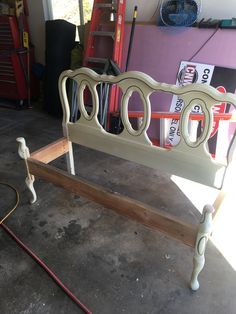 a white bed frame sitting on top of a floor next to a pile of tools