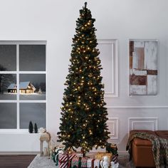 a decorated christmas tree in a living room next to a window with holiday presents on the floor