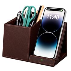 a cell phone and pen holder with pens, scissors, and pencils in it