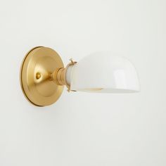 a white and gold wall light on a white wall with no one in the photo