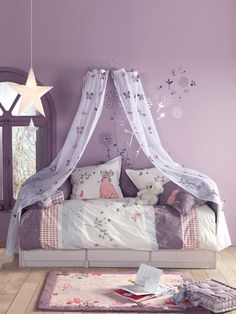 a canopy bed in a bedroom with purple walls