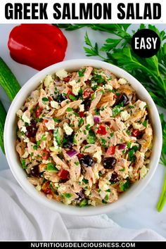 greek salmon salad in a white bowl with celery and red pepper on the side