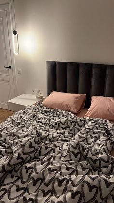 an unmade bed with black and white comforter on top of it in a bedroom