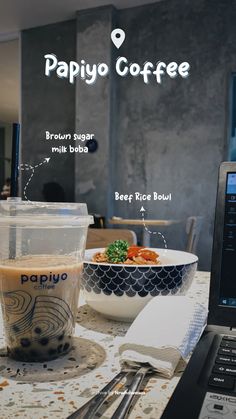 a laptop computer sitting on top of a table next to a bowl of food and a cup of coffee