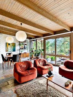 a living room filled with red couches and chairs next to a fire place in front of a large window