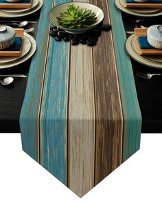 the table is set with blue and brown striped linens, white plates, and green succulents