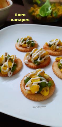 small crackers with corn and cheese on them are sitting on a white platter