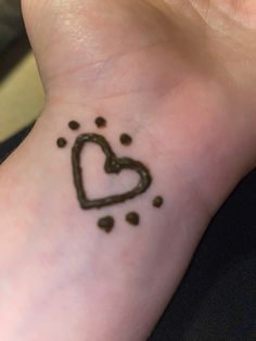 a small tattoo on the wrist of a person with a heart and dots around it