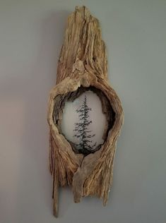 a piece of driftwood with a pine tree in the center is shown on a wall