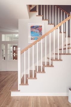 a white staircase with wooden handrails and hardwood flooring