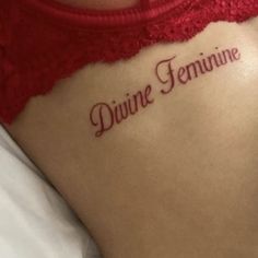 a close up of a person with a tattoo on their back that says divine feminine