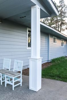 a white porch with two chairs and a table in front of the house on a sunny day