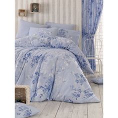 a bed with blue comforters and pillows in a room next to a basket on the floor