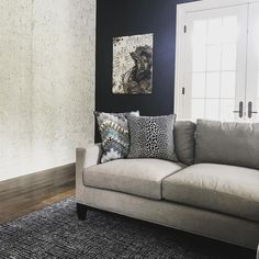 a living room with black walls and white trim on the wall, gray couches