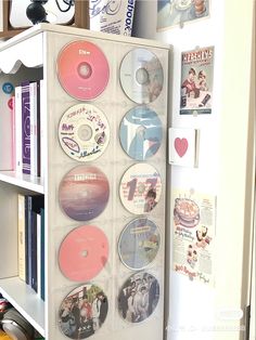 a white refrigerator freezer sitting next to a book shelf filled with cd's