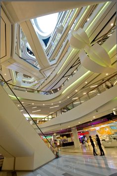 two people are standing in the middle of a large building with multiple floors and ceilings