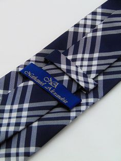 "Mens 100% silk plaid necktie. Features a midnight blue background with gray and white plaid pattern. Handmade from 100% silk, this special collection features a .75\" Eds Neckties logo at the bottom right front corner of every tie and a larger logo located on the tipping (Back of the tie). The label features the collection name (Nathaniel Alexandria) Named after my son Nathaniel and my daughter Alexandria. Expertly hand-made from 100% silk you can select your length from 57\" to 63\" (Great for Classic Plaid Business Suit And Tie Accessories, Blue Classic Ties For Father's Day, Semi-formal Navy Standard Tie, Classic Blue Standard Tie, Midnight Blue Background, Blue Silk Neckwear With Ties, Blue Semi-formal Necktie, Classic Plaid Standard Tie, Purple Gothic