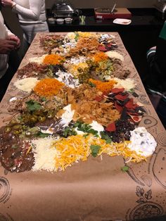 a long table covered with lots of different types of food on top of paper bags