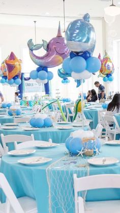 there are many blue and white balloons hanging from the ceiling in this dining room area