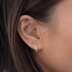 a woman's ear is shown with two small diamond hoops on the side