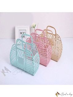 three different colored baskets sitting next to each other on a white surface with a framed photo in the background