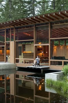 a person sitting on a dock in front of a house that is built into the water